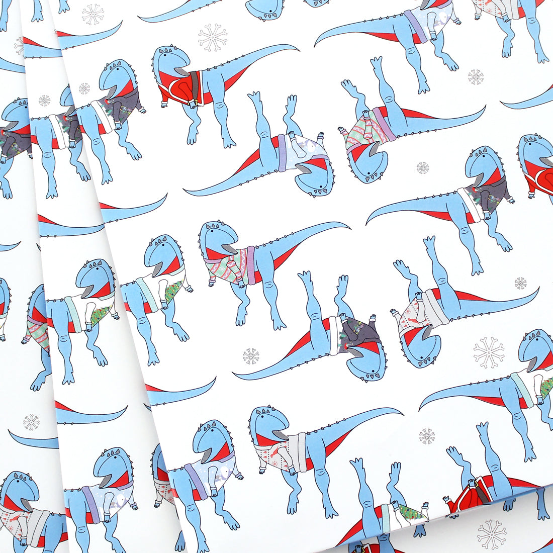 3 sheets of Dinosaur Ugly Christmas Jumper Wrapping Paper fanned out
