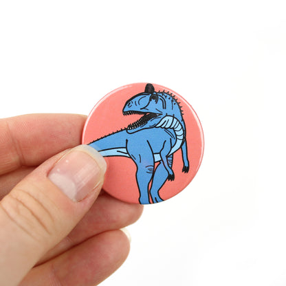 hand holding a mini cryolophosaurus badge