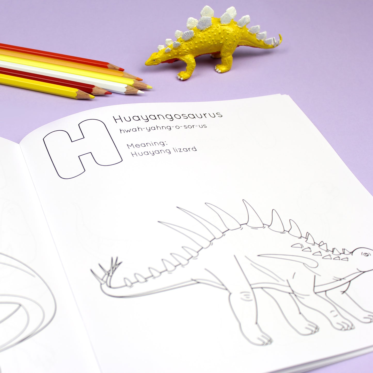 Inside page of ABC Dinosaur colouring book. The page features black line illustration of a Huayangosaurus dinosaur with its name, pronunciation and meaning above it.