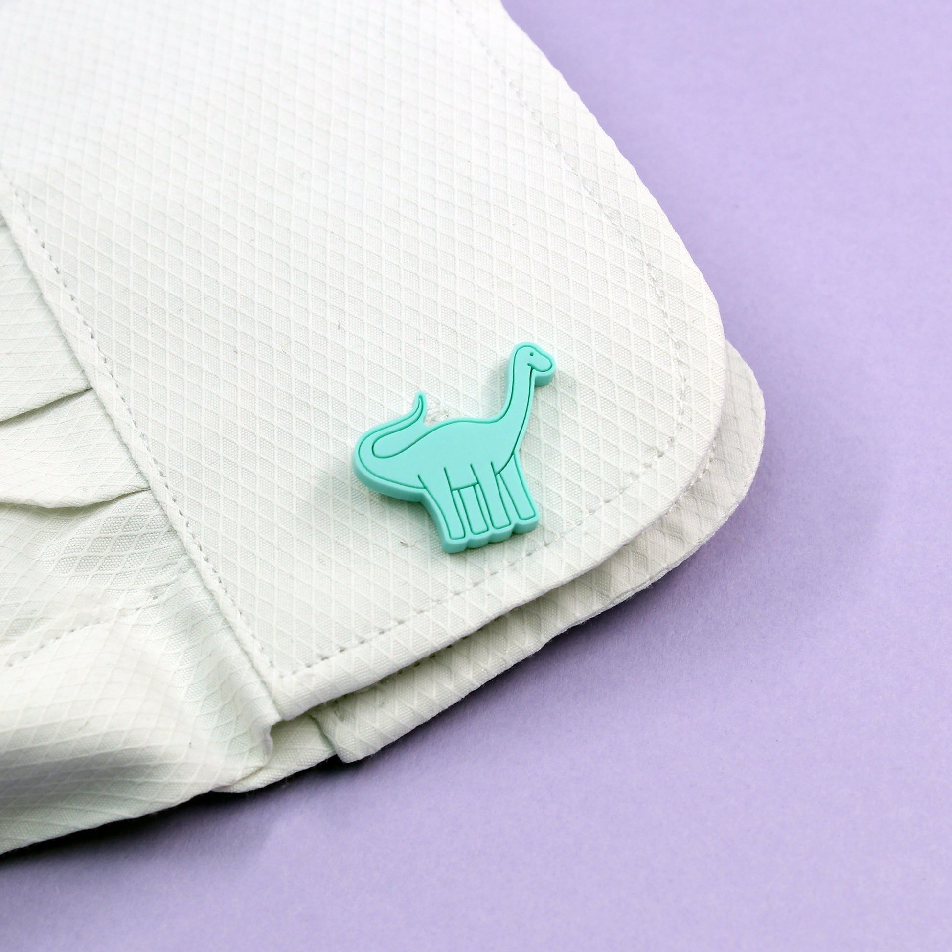 a mint brontosaurus cufflink on a white shirt
