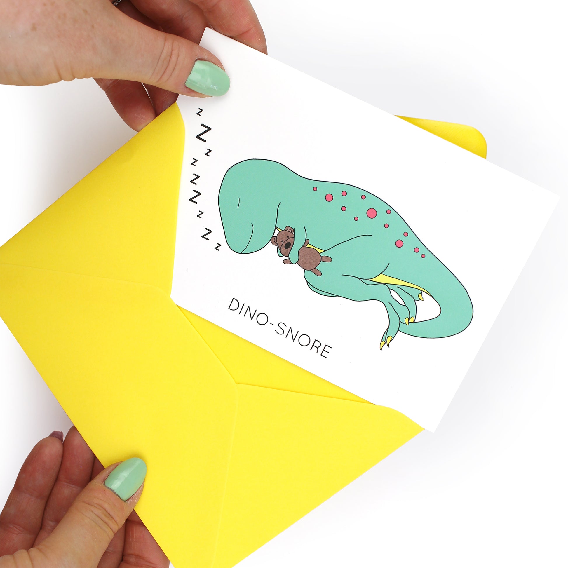 hands holding an envelope while removing the dino-snore dinosaur card from the envelope
