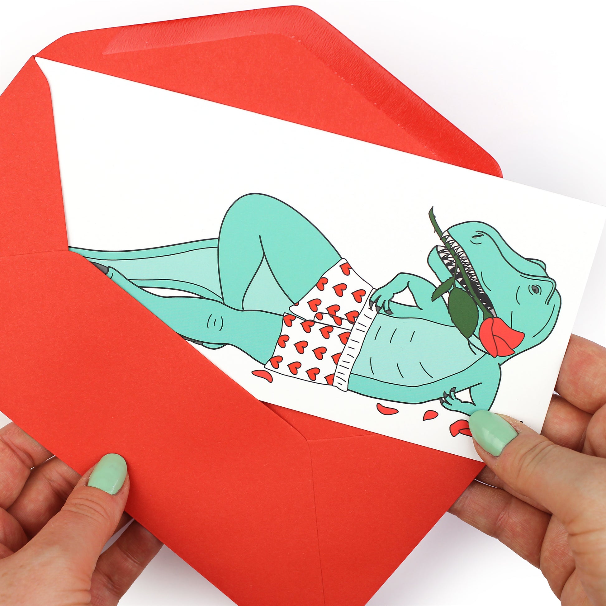 hands holding an envelope while removing the sexy t-rex dinosaur card from the envelope