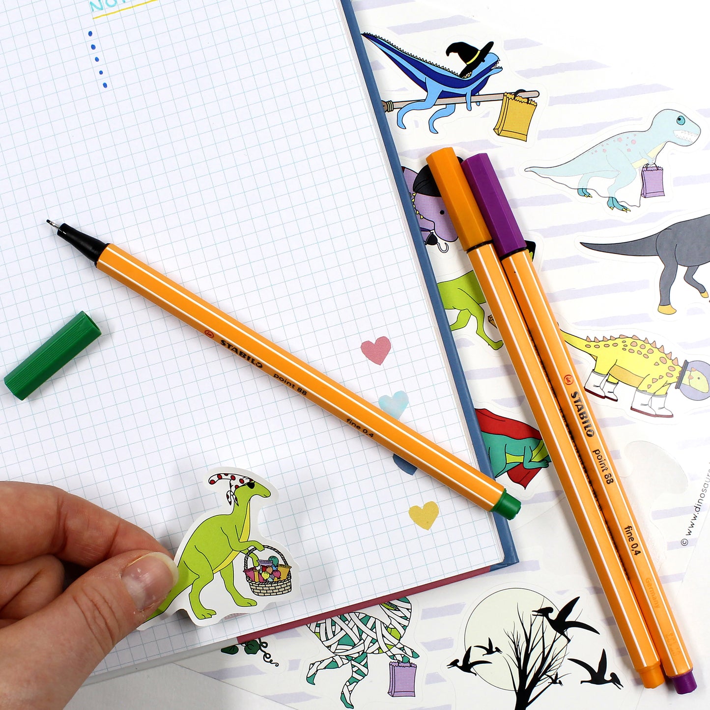 Halloween dinosaur sticker on a notebook with sheet and pens
