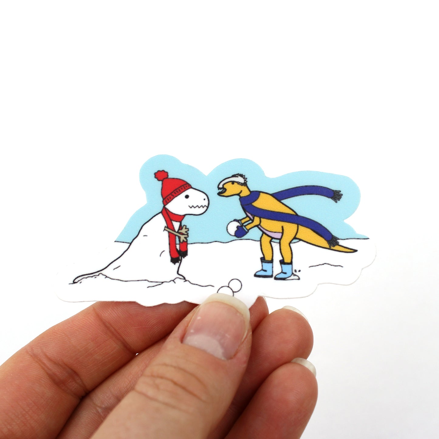 dinosaur making a snow-rex snow man sticker held by a hand