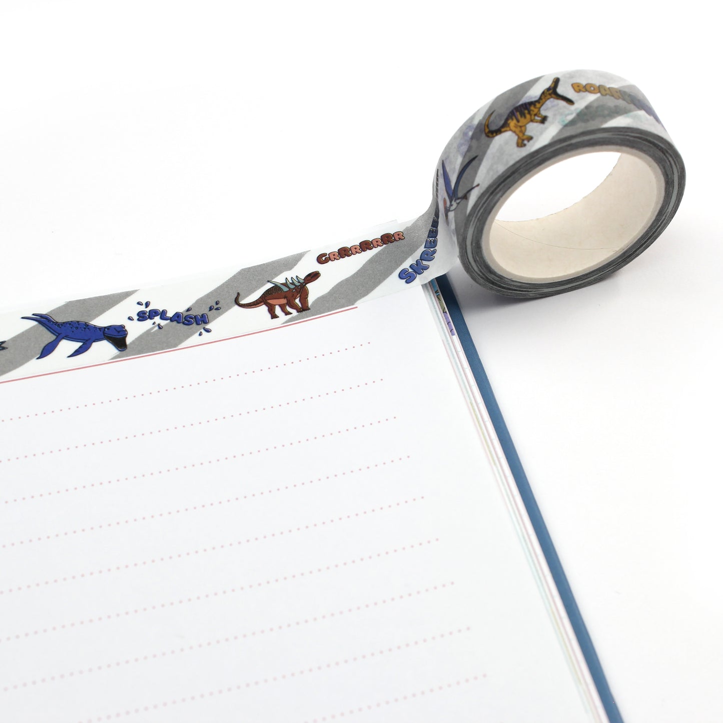 A roll of dinosaur words washi tape along the top edge of a notebook