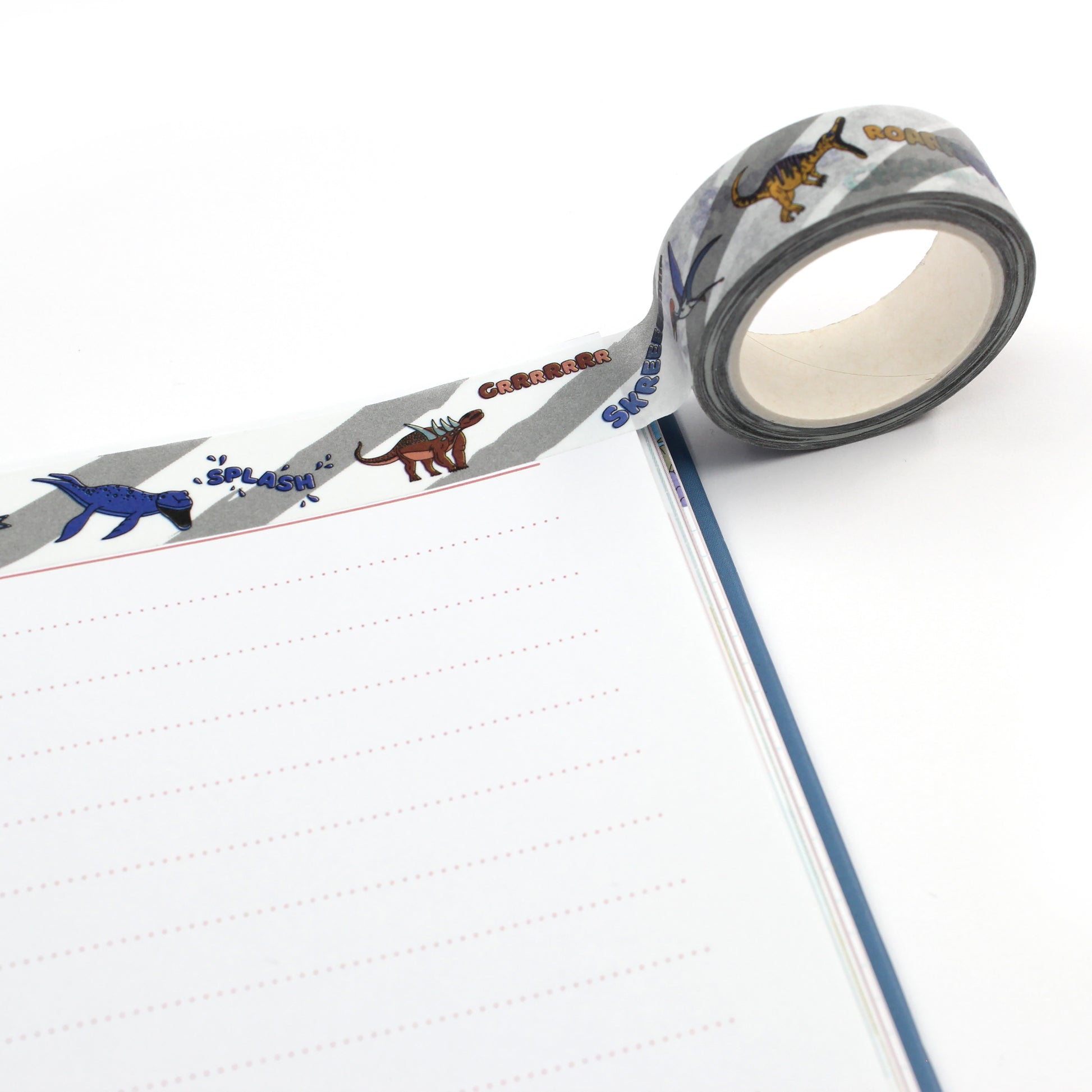 A roll of dinosaur words washi tape along the top edge of a notebook