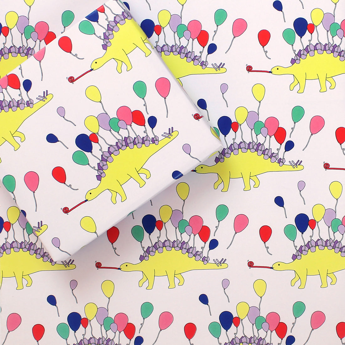 a sheet of Dinosaur Party Animal Wrapping Paper with a small box on it wrapped in the same design
