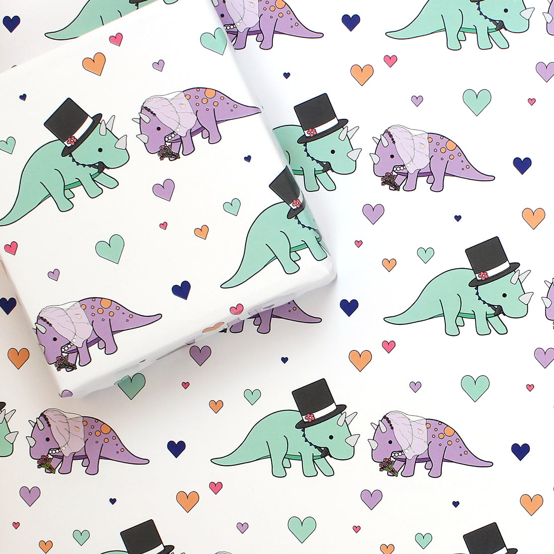 a sheet of triceratops wedding dinosaur wrapping paper with a box on top that is also wrapped in the same paper