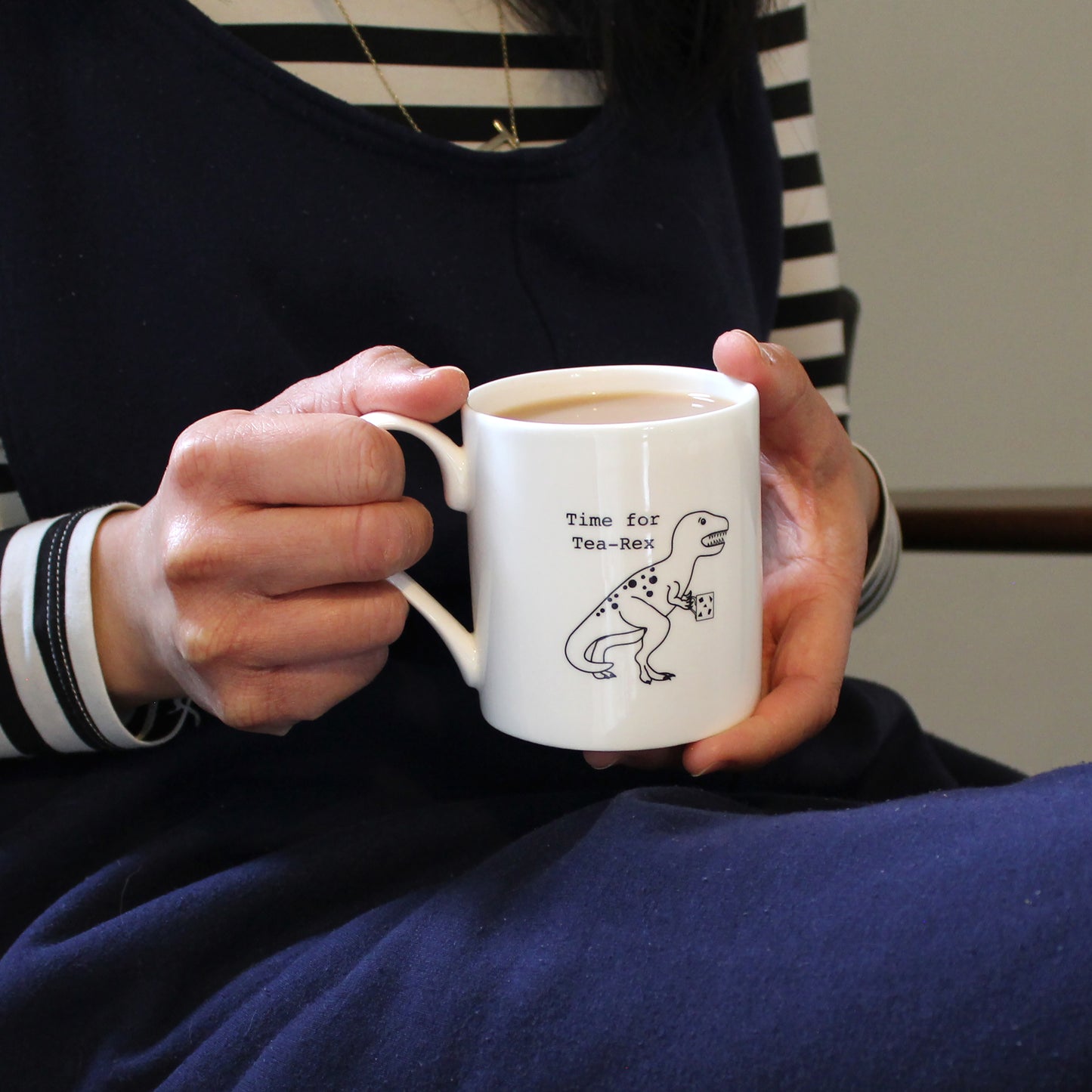 Time for Tea-Rex Mug held by a person in a navy jumpsuit and stripe top