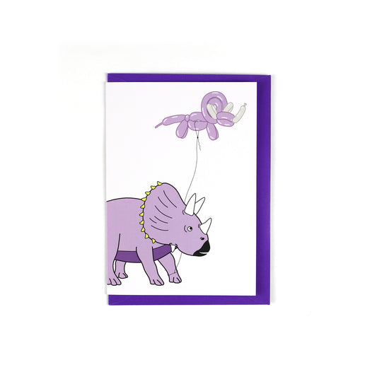 greeting card featuring a triceratops dinosaur holding a balloon dinosaur on a string