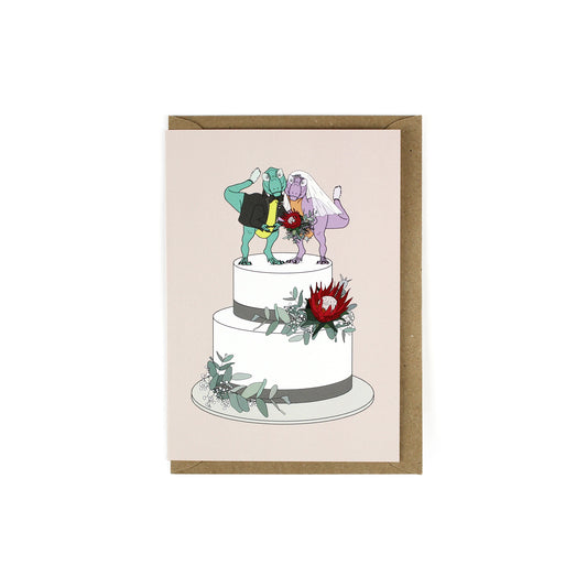 greeting card featuring two t-rex on a wedding cake on a pale pink background