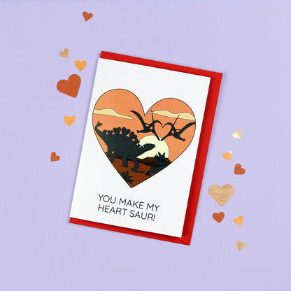You make my heart saur dinosaur card on a purple background with metallic paper hearts scattered around it