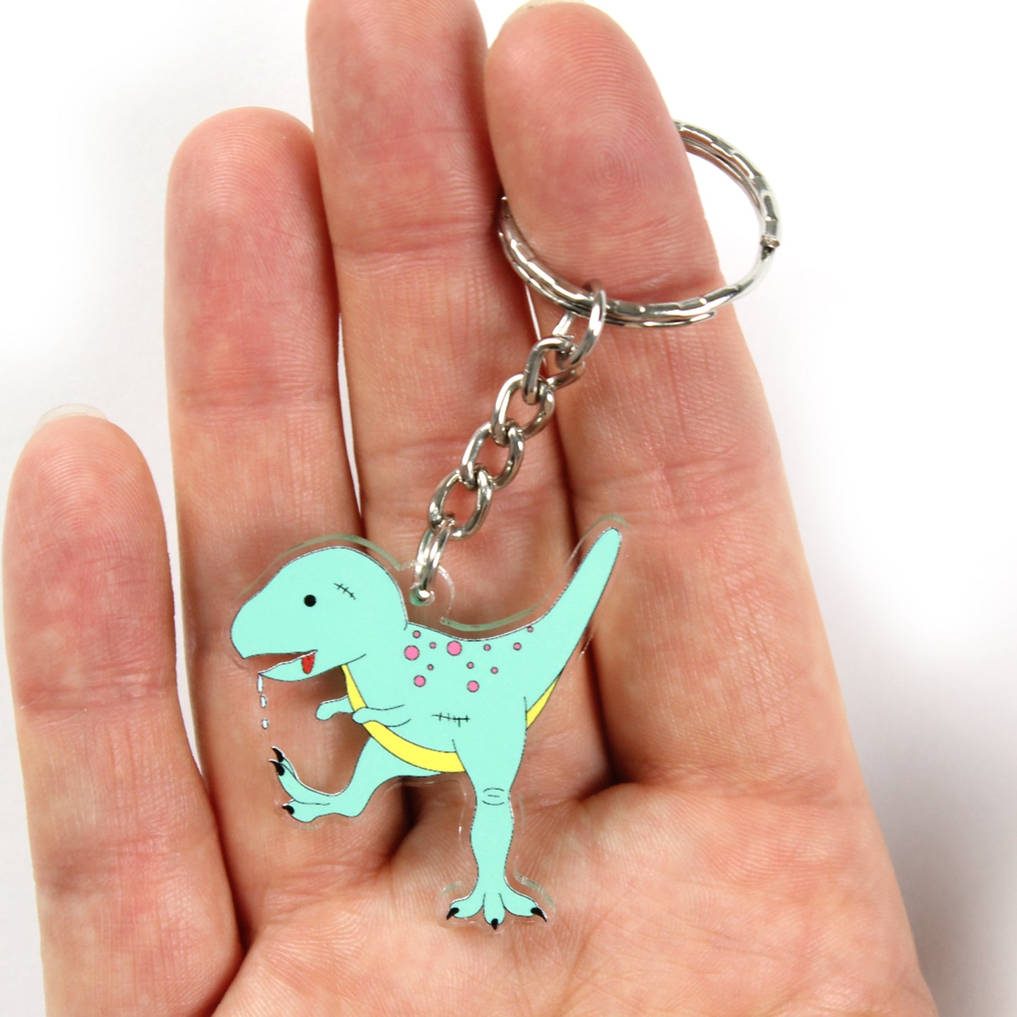 Zombie T-Rex dinosaur keyring on a hand with the split ring over a finger