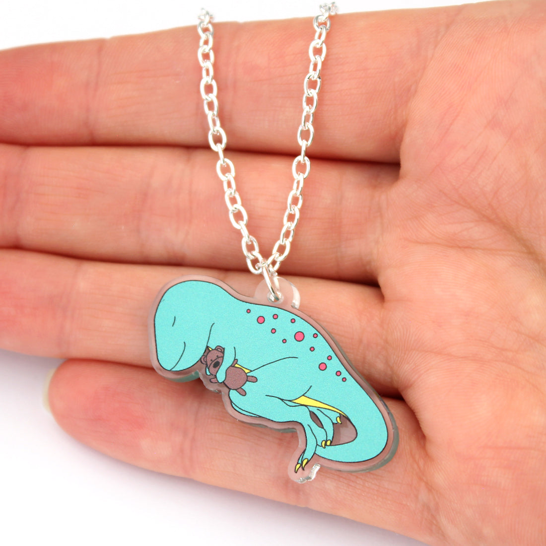 dino-snore t-rex dinosaur necklace on a hand