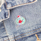 a Santa Claws acrylic pin on a denim jacket