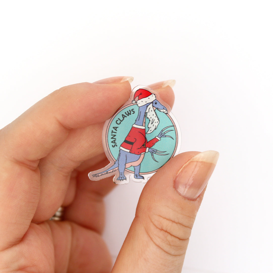 Hand holding a Santa Claws acrylic pin