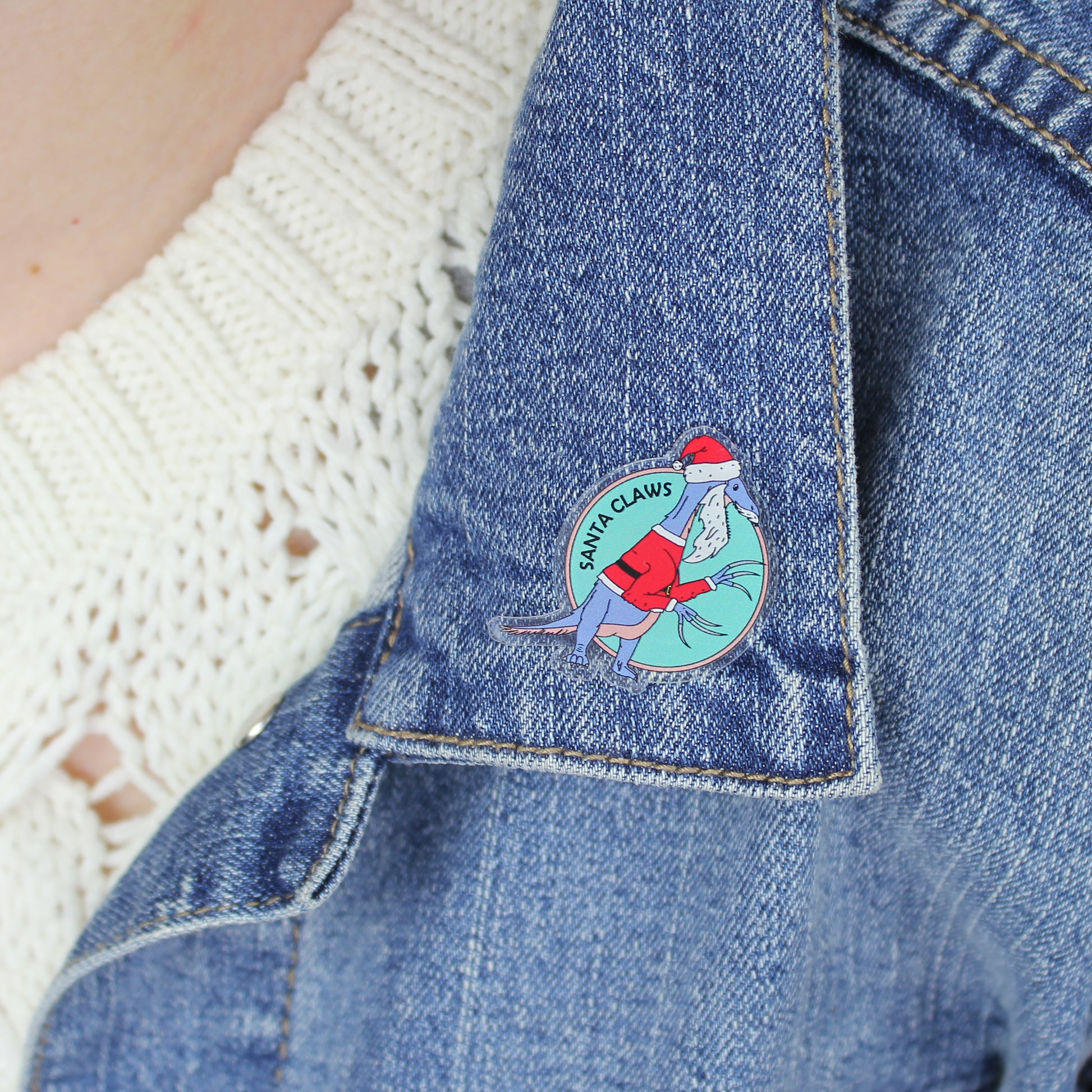 a Santa Claws acrylic pin on a denim jacket