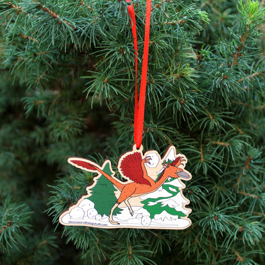 wooden Christmas decoration featuring a dinosaur throwing snowballs hanging on a Christmas Tree