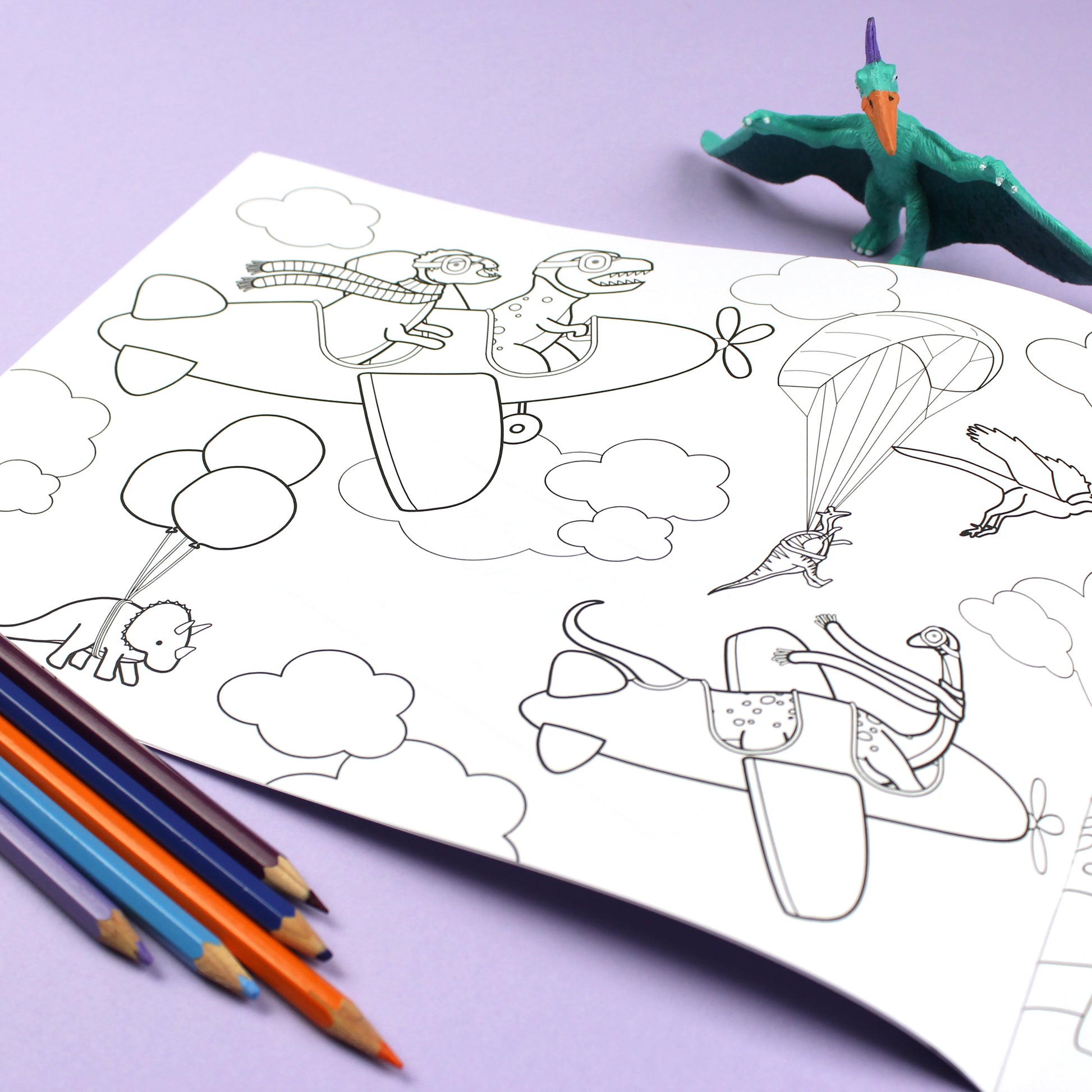 Inside page of Dinosaurs Doing Stuff colouring book. The page features black line illustrations of dinosaurs flying planes, hanging from balloons and parasailing among clouds