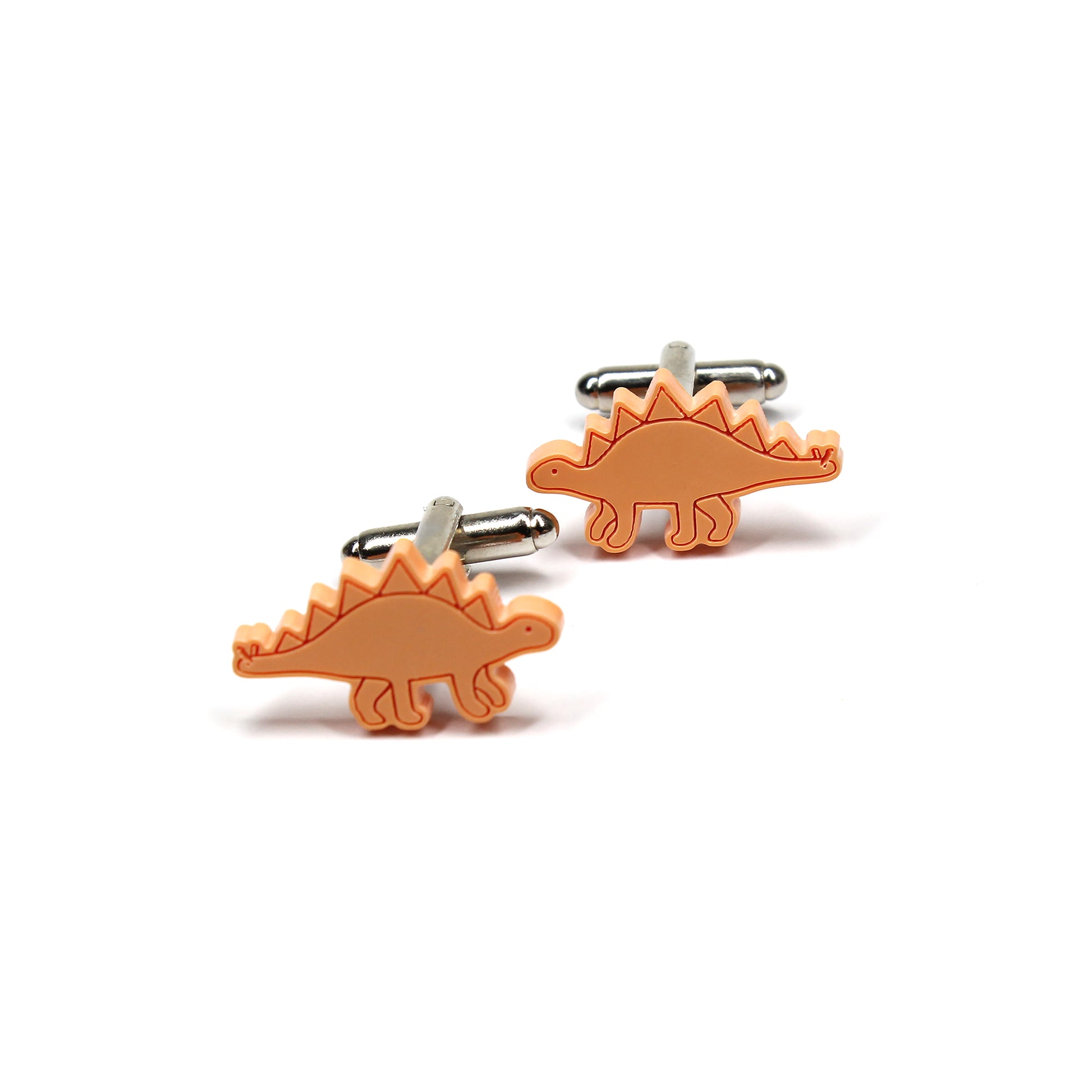 a pair of orange stegosaurus cufflinks on a white background