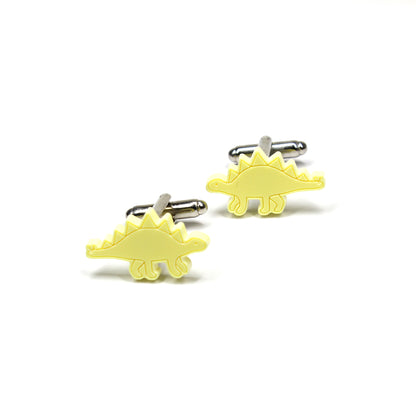a pair of yellow stegosaurus cufflinks on a white background
