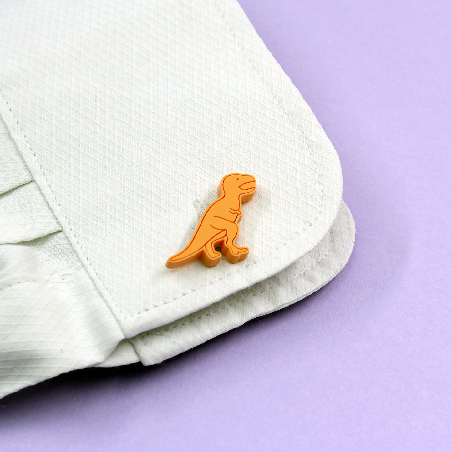 orange tyrannosaurus-rex dinosaur cufflinks on a shirt cuff