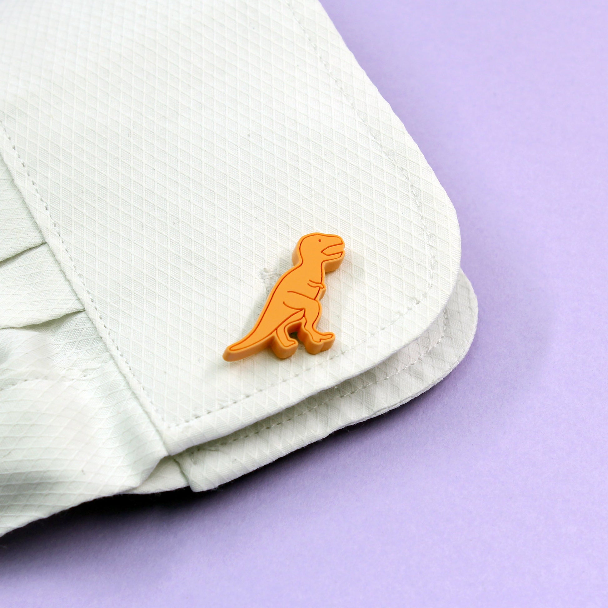 orange tyrannosaurus-rex dinosaur cufflinks on a shirt cuff