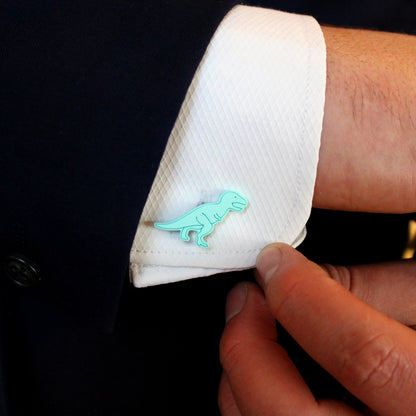green tyrannosaurus-rex cufflinks on a shirt with a hand holding the edge of the shirt
