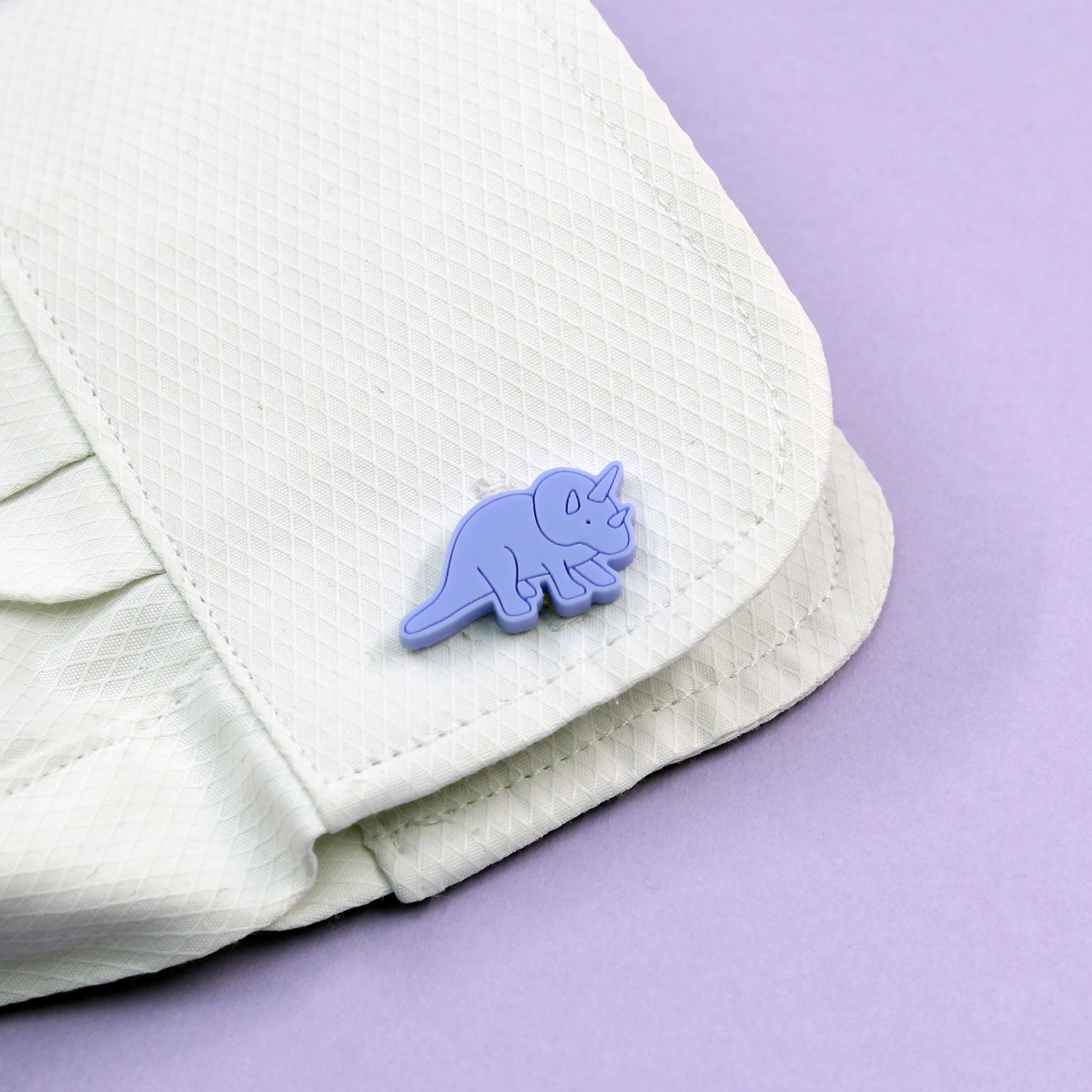 a blue triceratops cufflink on a white shirt cuff