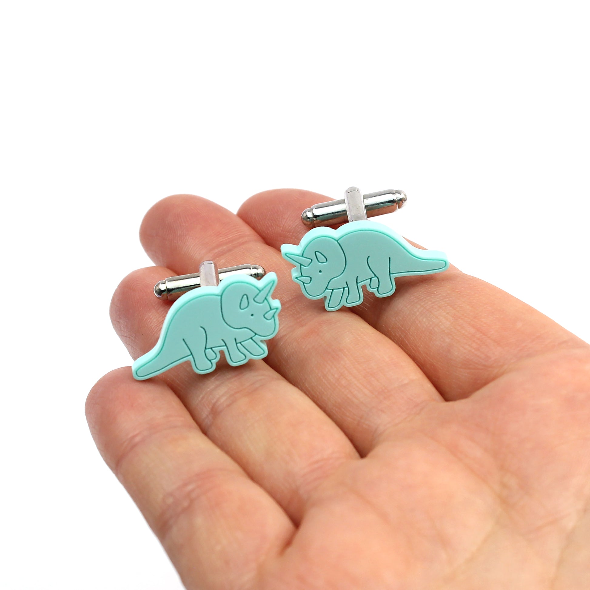 a pair of mint triceratops cufflink on a hand