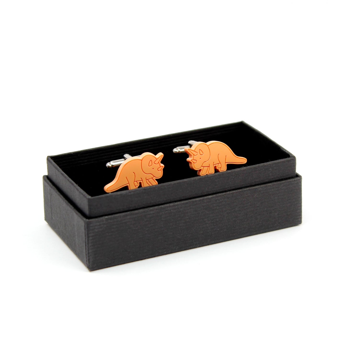 a pair of orange triceratops cufflinks in a black box