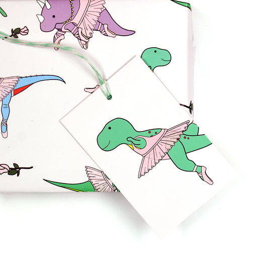 Ballet dinosaur gift tag sitting on a box covered with matching wrapping paper