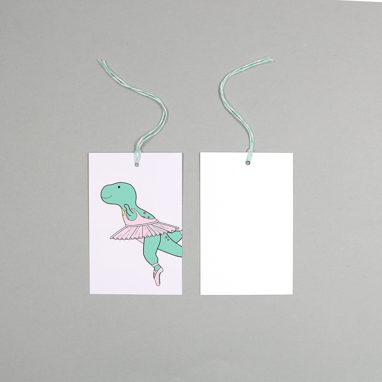 flat lay showing the front and back of the ballet dinosaur gift tag on a grey background