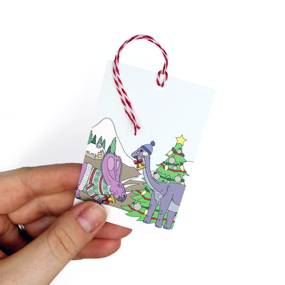 hand holding a winter dinosaur gift tag