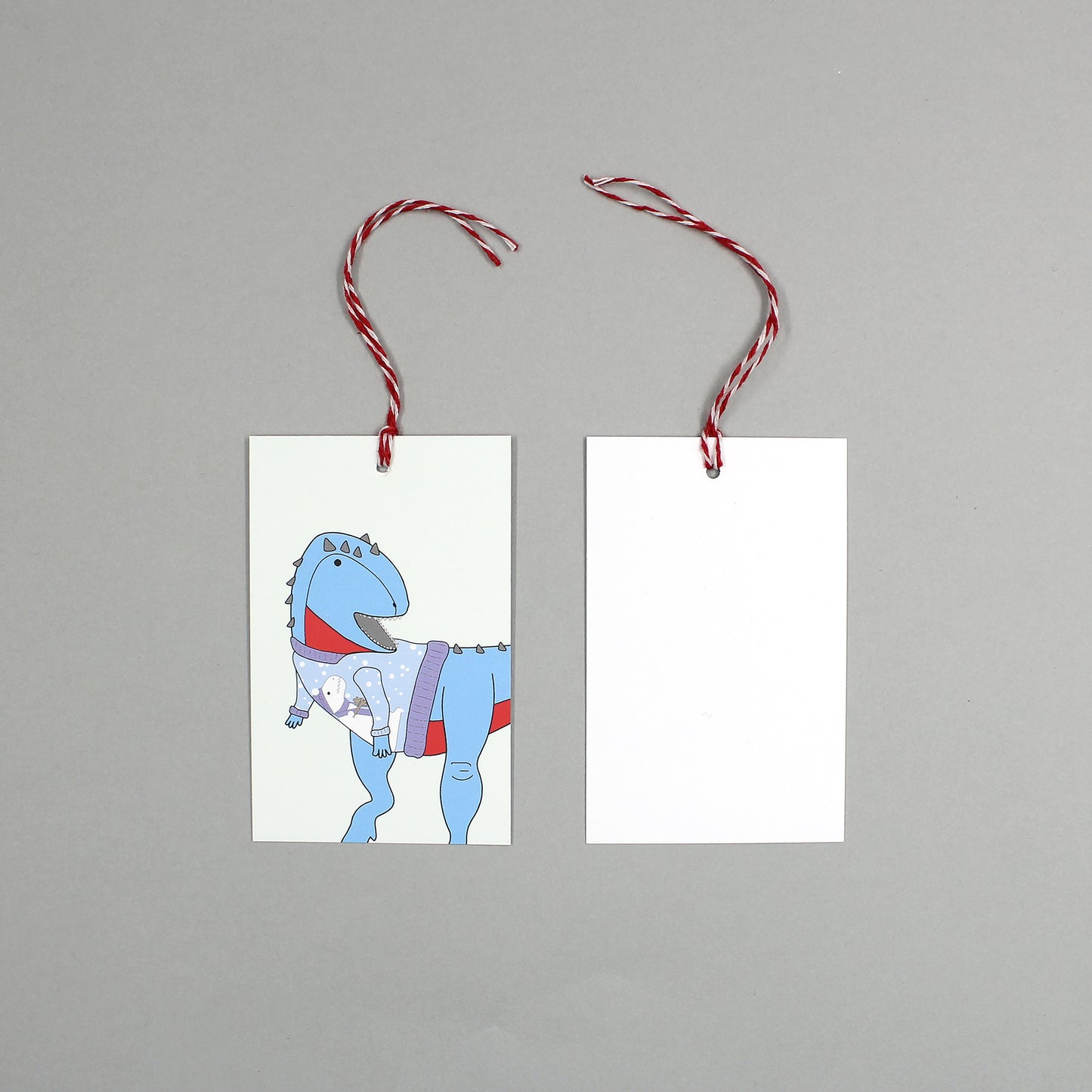 flat lay showing the front and back of the ugly Christmas jumper dinosaur gift tag on a grey background