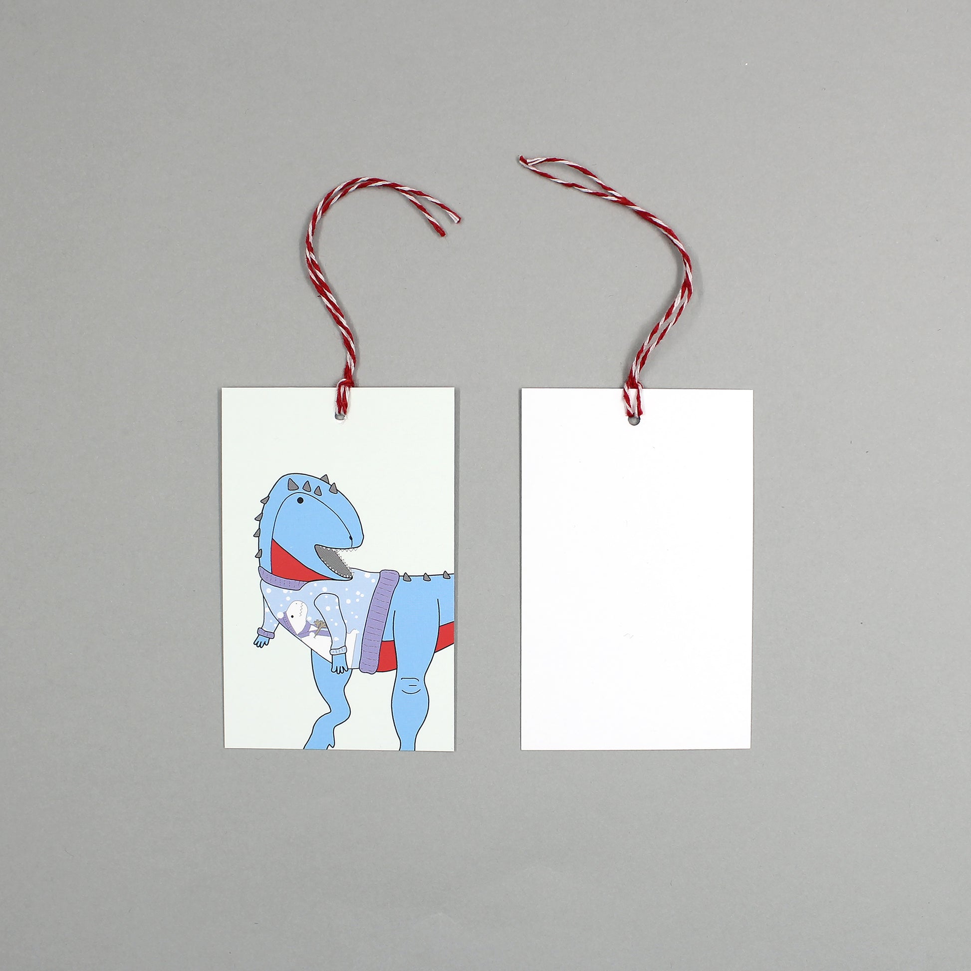 flat lay showing the front and back of the ugly Christmas jumper dinosaur gift tag on a grey background
