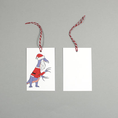flat lay showing the front and back of the dinosaur Santa Claws gift tag on a grey background