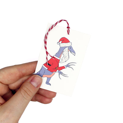 hand holding a dinosaur Santa Claws gift tag
