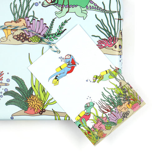 Under the Sea dinosaur gift tag sitting on a box covered with matching wrapping paper