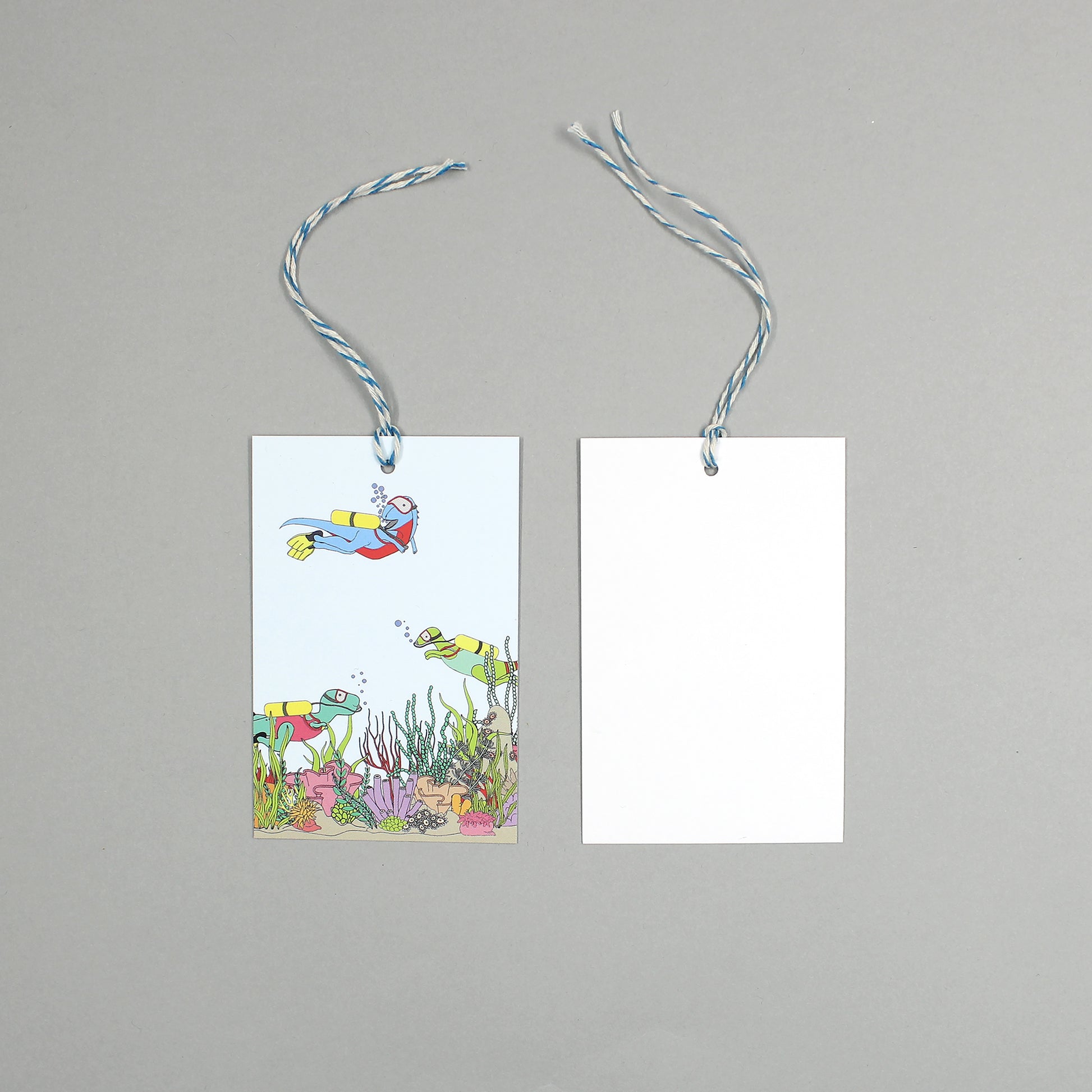 flat lay showing the front and back of the under the Sea dinosaur gift tag on a grey background