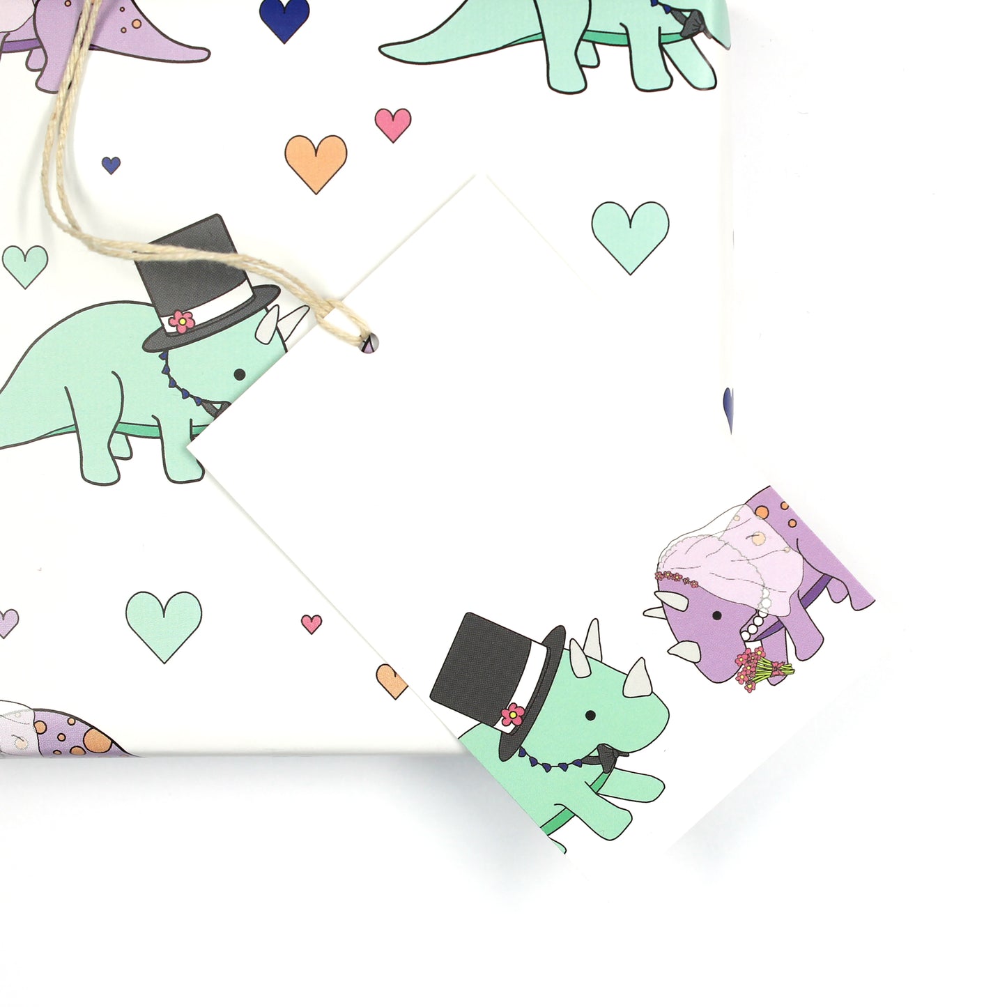 Wedding dinosaur gift tag sitting on a box covered with matching wrapping paper