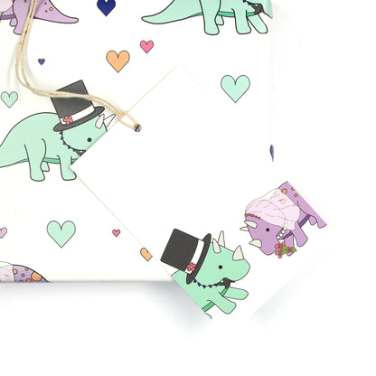 Wedding dinosaur gift tag sitting on a box covered with matching wrapping paper