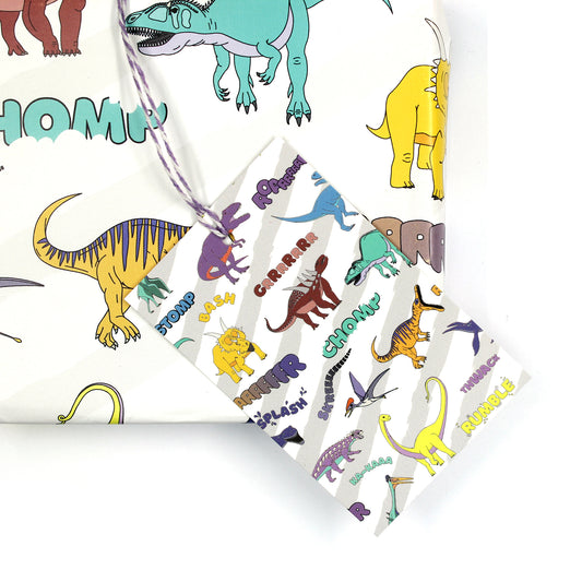 dinosaur words gift tag sitting on a box covered with matching wrapping paper