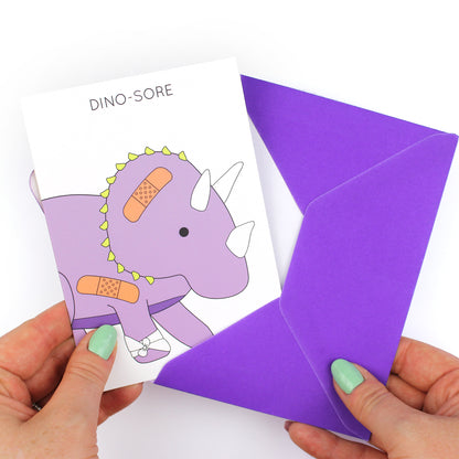 hands holding an envelope while removing the dino-snore dinosaur card from the envelope