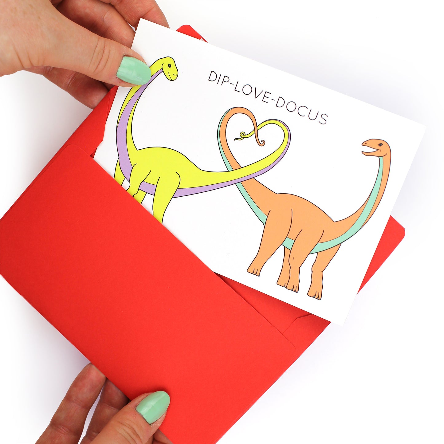 hands holding an envelope while removing the dip-love-docus dinosaur card from the envelope