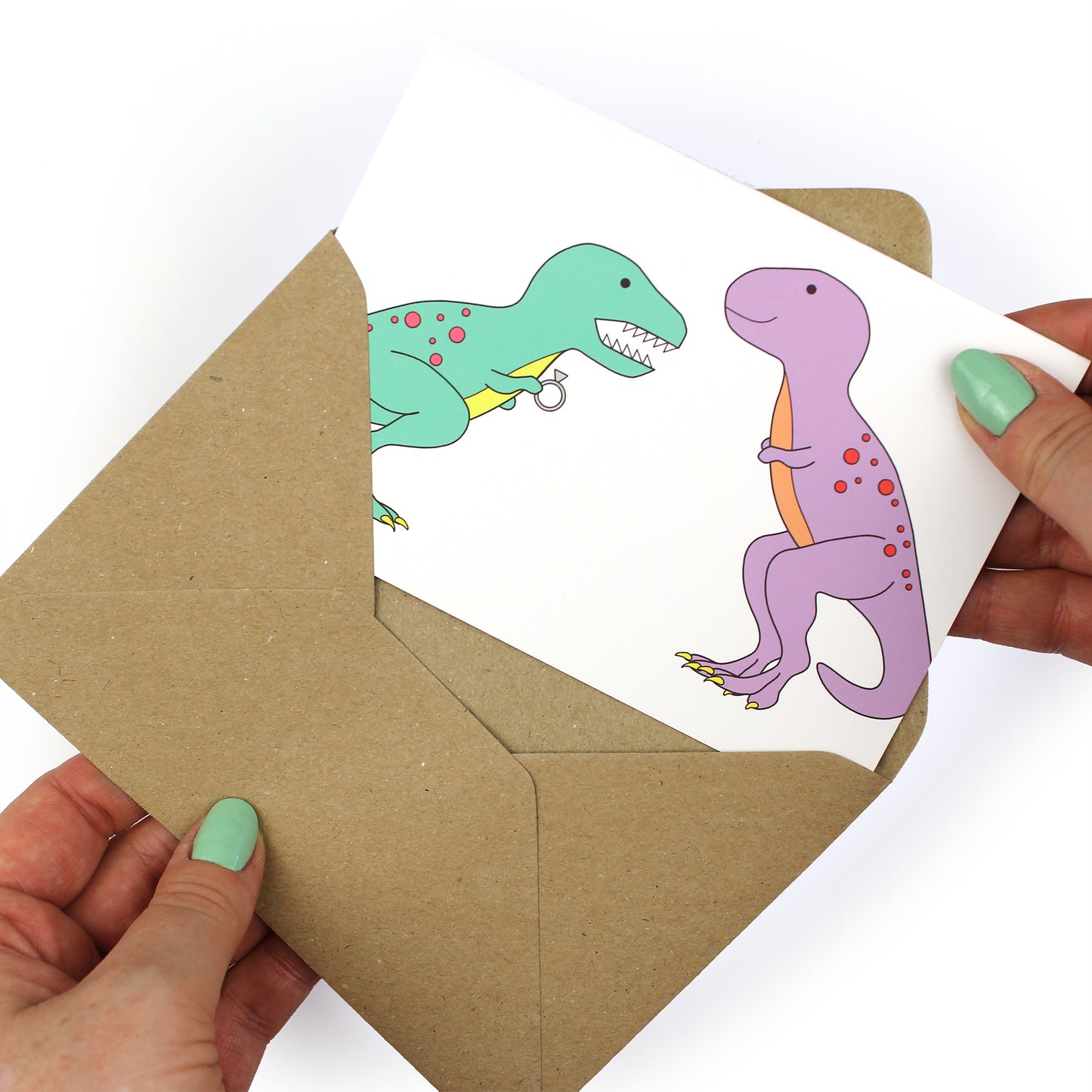 hands holding an envelope while removing the dinosaur engagement card from the envelope
