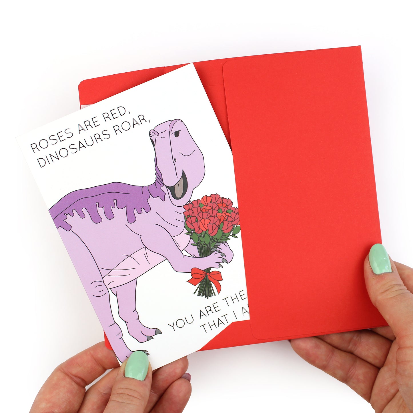 hands holding an envelope while removing the roses are red dinosaur card from the envelope