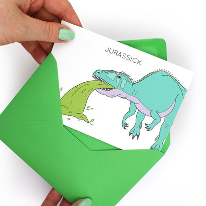 hands holding an envelope while removing the jurassick dinosaur card from the envelope