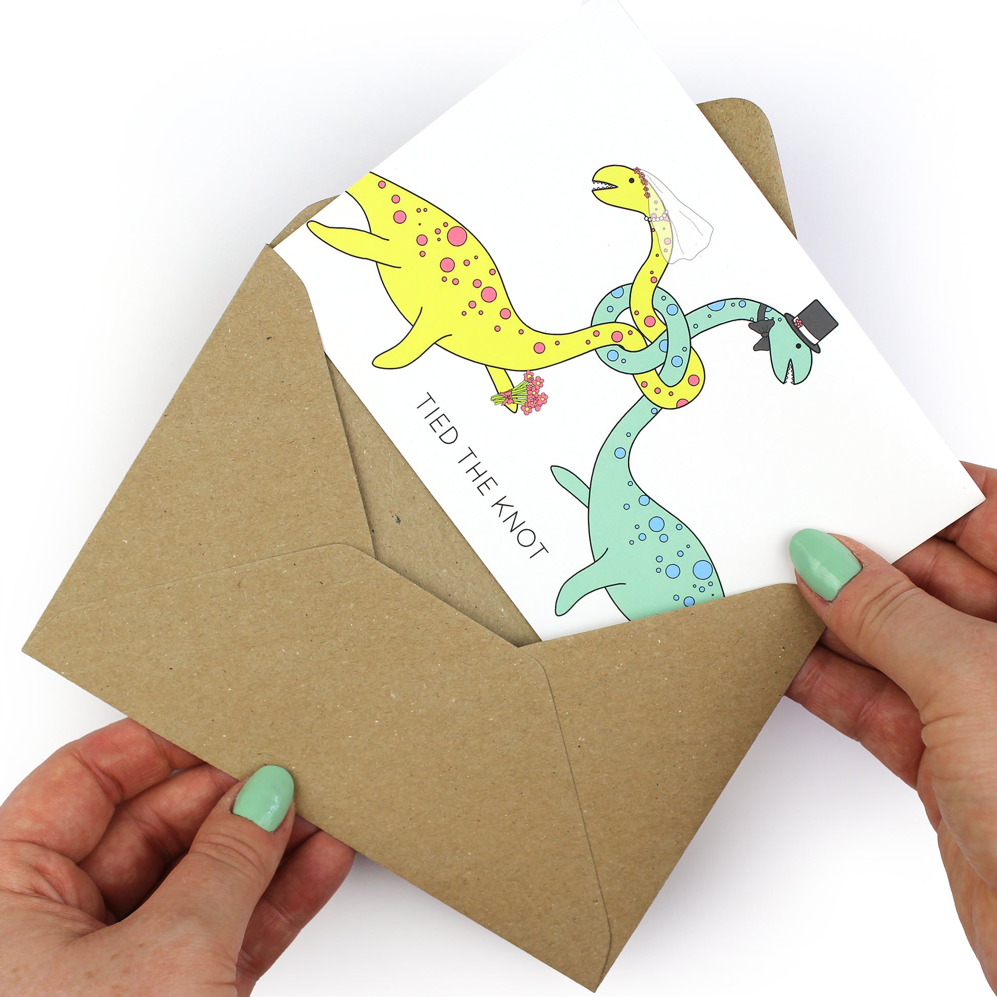 hands holding an envelope while removing the tied the knot dinosaur card from the envelope