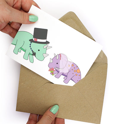hands holding an envelope while removing the dinosaur wedding card from the envelope